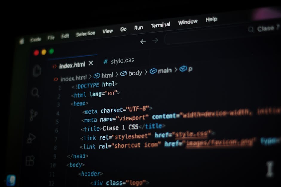A close-up photograph of a computer screen displaying lines of colourful programming code, including syntax highlighting in shades of red, green, blue, yellow, and white text on a dark background. The